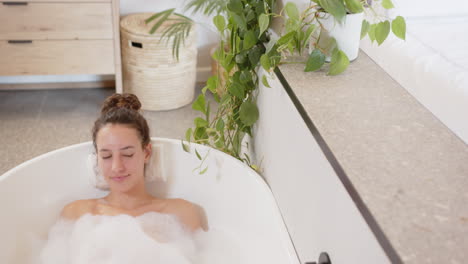 relaxing in bathtub, woman enjoying bubble bath with plants around, copy space