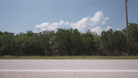 a white suv drives along a sunny summer highway in the texas hill country - slider left to right