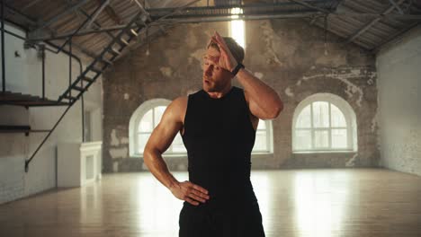 portrait of a male athlete in a black sports uniform who wipes sweat from his forehead shows a like sign and leaves