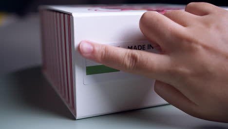 Hands-applying-MADE-IN-INDIA-flag-label-on-a-shipping-cardboard-box-with-products