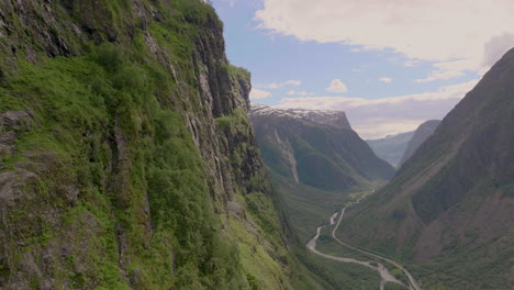 magical gudvangen valley, aerial drone flies past lush green cliffs over river