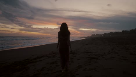 Chica-Solitaria-En-La-Orilla-De-Una-Playa-De-Arena-Paseando-Durante-La-Puesta-De-Sol