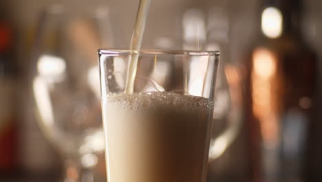 close up of craft beer being poured in to an empty pint glass, light background