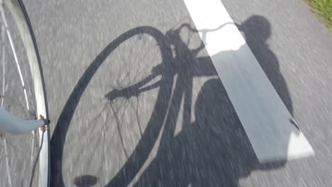 shadow of cyclist biking on asphalt road, 60 fps