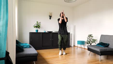 young man dances in the living room and trains his dance steps