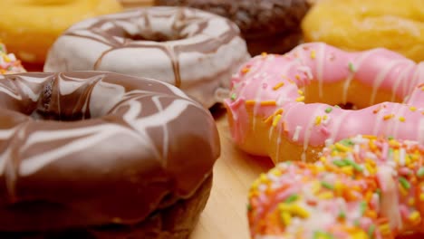 various flavors of donuts on a rotating wooden plate.