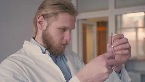 a young doctor with long, blond hair prepares a syringe