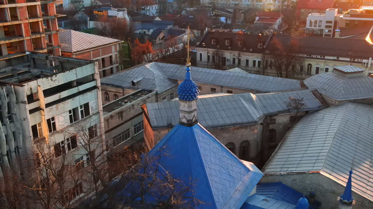 Aerial drone view of a church with blue roof, bare trees, old and unfinished buildings around it in Chisinau, Moldova
