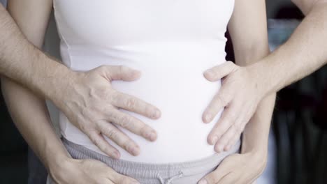 happy married couple holding hands on belly