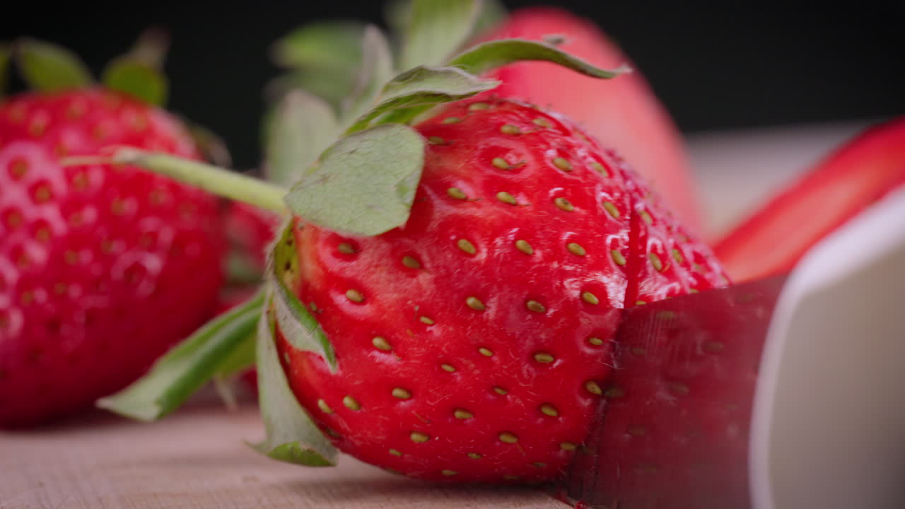 Strawberry being cut up with other strawberries in background