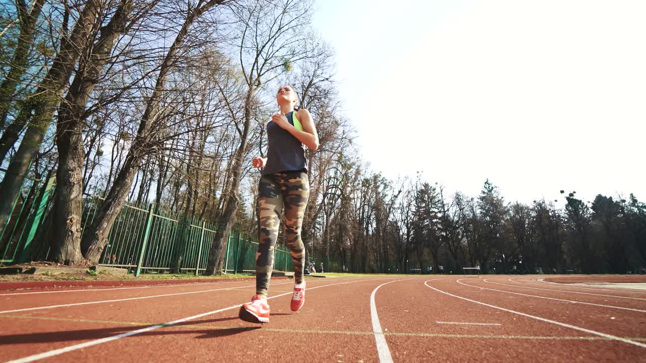 Summer outdoors training. Athlete woman starting running on running track. Beautiful girl doing exercises.