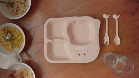 person putting biscuits on divided kids plate - preparing and plating kids meal