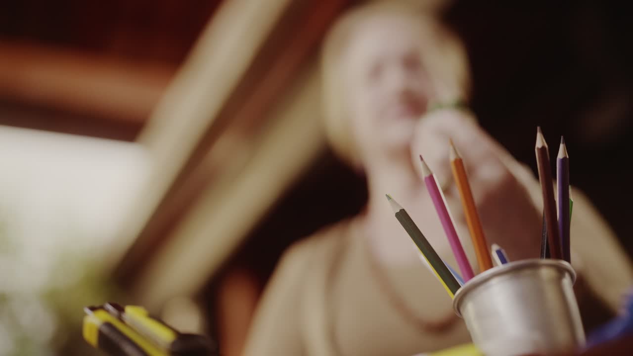 Close-up of colored pencils and art supplies with a person in the background