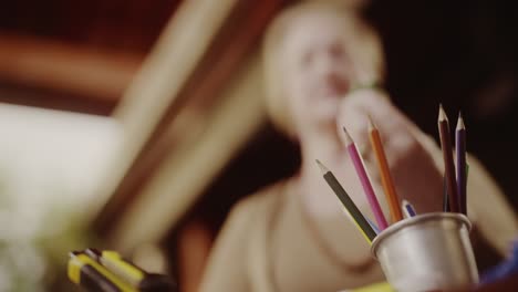 close-up of colored pencils and art supplies with a person in the background