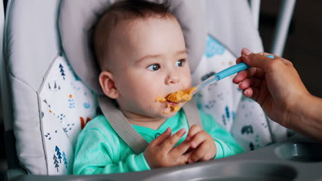 little toddler eating vegetables sitting in the chair. cute kid sticking out tongue during meal time. close up.