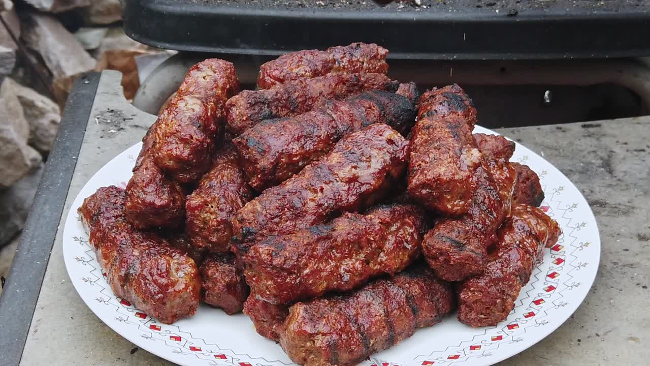 Man put grilled sausage on the plate using tongs. Slow motion. Close up