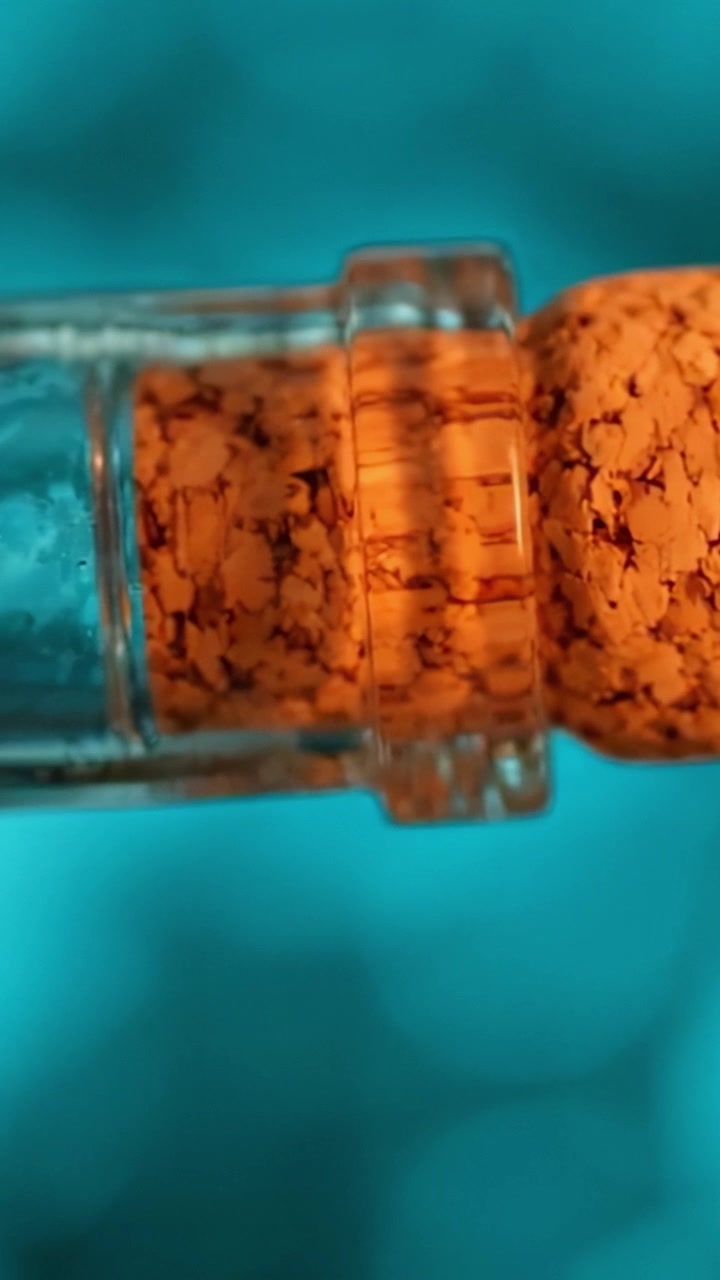 Un primer plano de un tapón de corcho en una botella contra un vibrante fondo azul, mostrando su textura única y detalle de color.