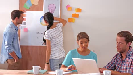 Creative-team-using-laptop-computer-while-their-colleagues-looking-at-color-sample