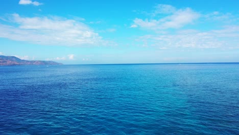 Hermosa-Isla-De-Agua-De-Mar-Turquesa-Cristalina-Y-Montañas-Cubiertas-De-Nubes-Blancas-Y-Esponjosas-En-El-Fondo