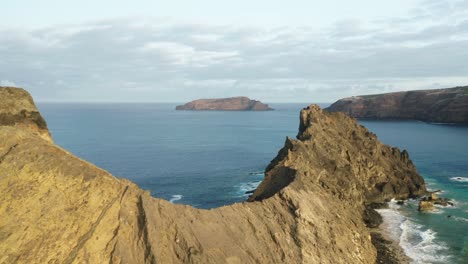 rugged ridge of north side of ilhéu da cal with blue ocean water, aerial