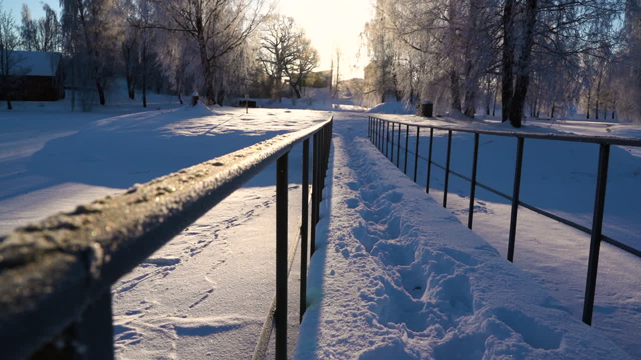 pequeño puente peatonal cubierto de una profunda capa de nieve con marcas de caminata en el soleado día de invierno