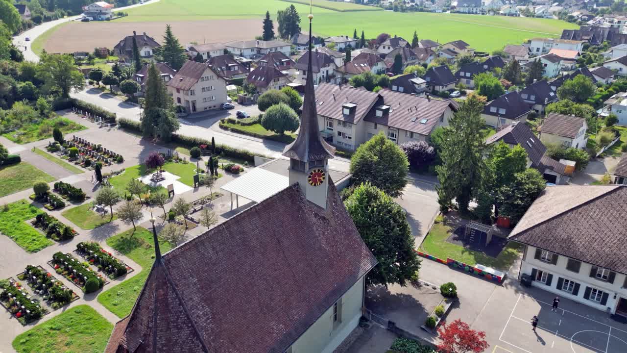 Drone flight with a DJI drone at low level over the beautiful reformed church from 1664 in B&auml;tterkinden and the cemetery near Bern in Switzerland