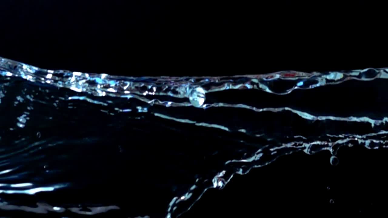 Acqua su sfondo nero. Slow motion.