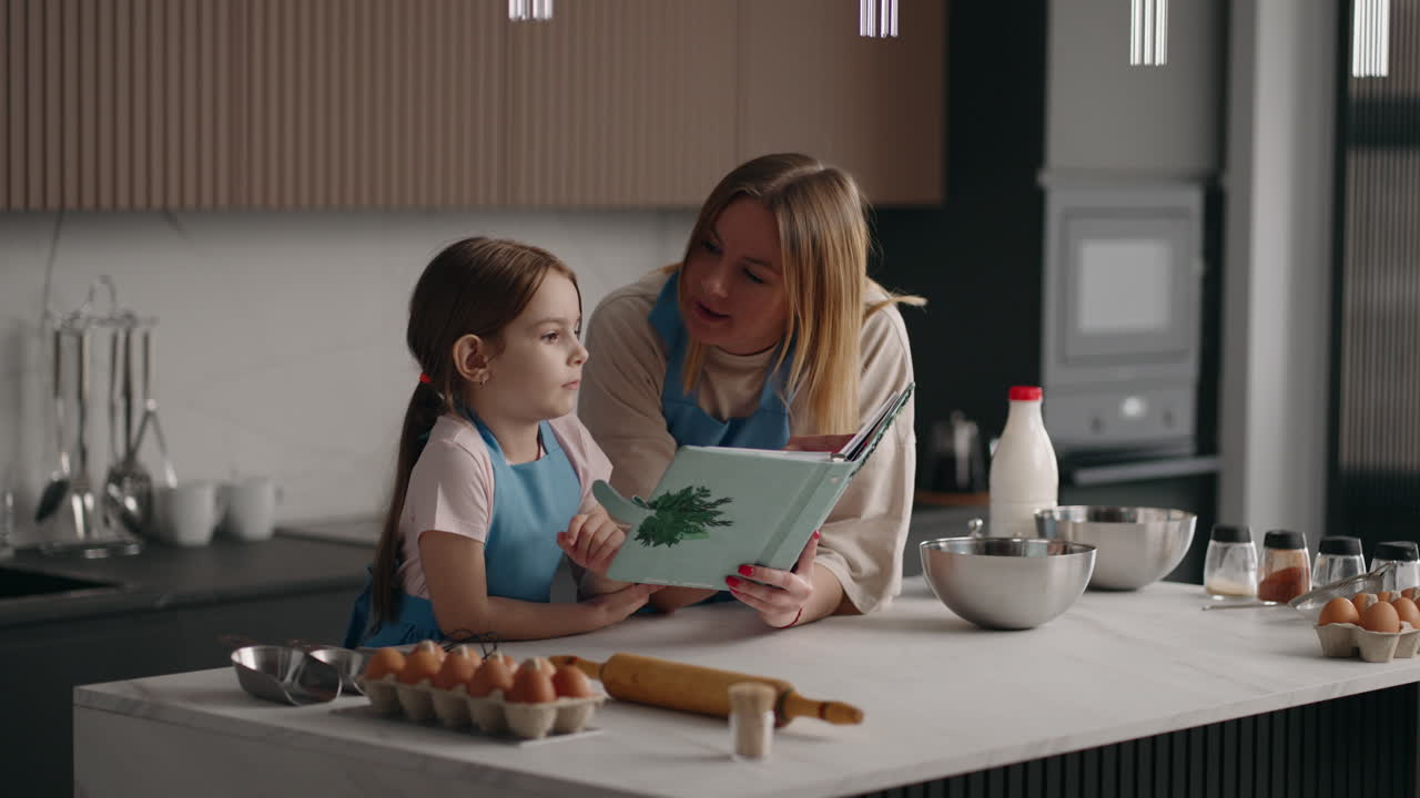 cocinando panqueques en la cocina de la casa la niña y la madre están leyendo el recibo en el libro de cocina