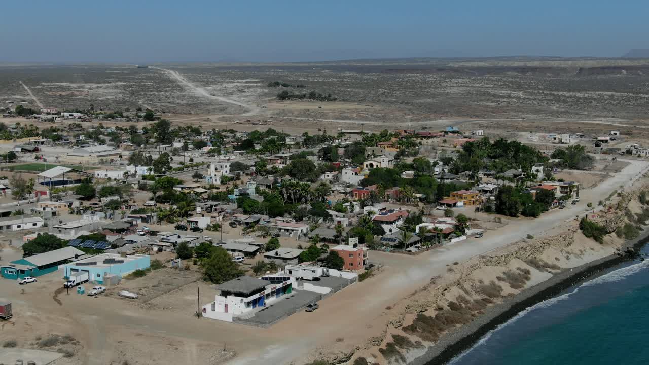 vista aérea que avanza, vista panorámica de la ciudad de san juanico, california sur, méxico, pastizales secos y cielo azul en el fondo