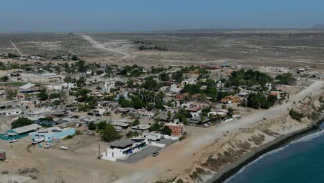 aerial view moving forward shot, scenic view town of san juanico, california sur, mexico, dry grassland and blue sky in the background