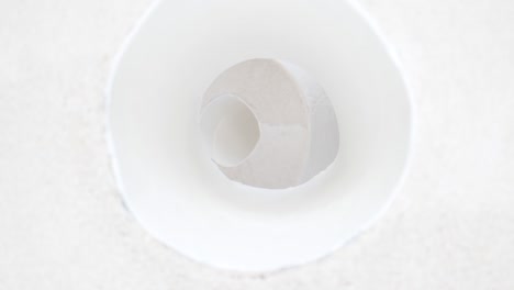 camera moves through a roll of toilet paper. human hand picks up one roll.