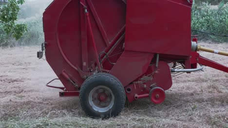 a round baler discharges a fresh wheat bale during harvesting.