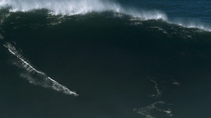 Slow motion of a big wave surfer riding a monster wave in Nazaré, Portugal