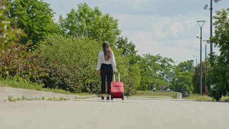 woman walking on the sidewalk while pulling along a wheeled luggage bag, handheld wide shot