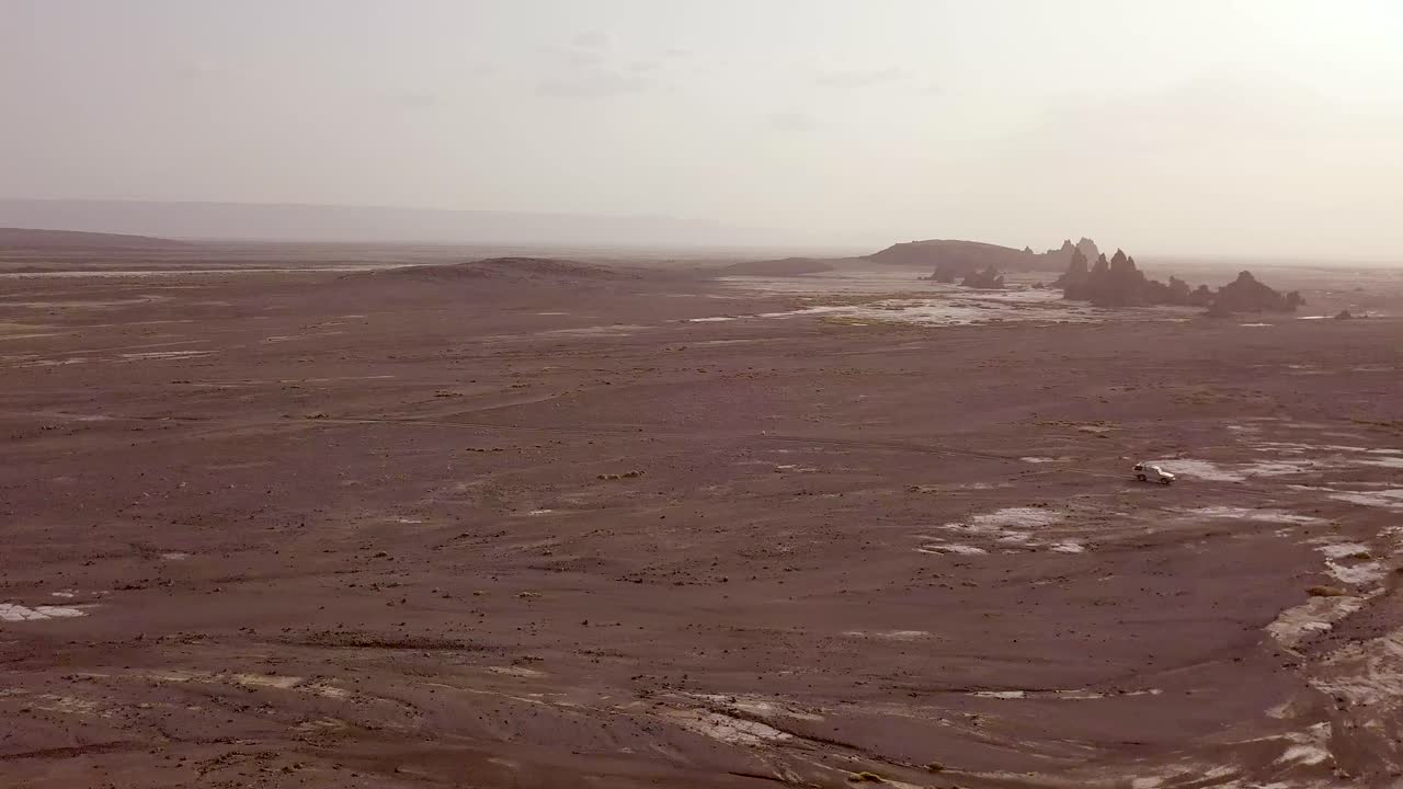 Good aerial over two 4 WD jeeps driving across a wild and rugged landscape in Djibouti or Somalia