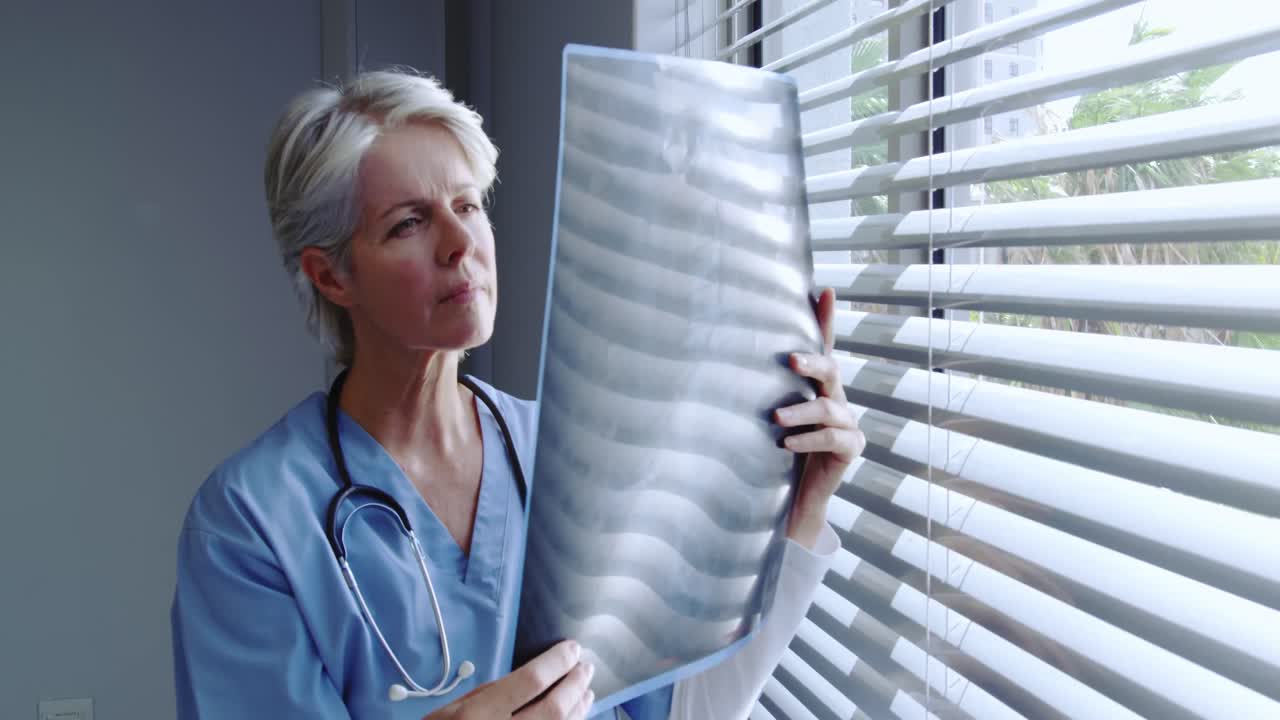 Front view of mature Caucasian female doctor looking at x-ray report in hospital