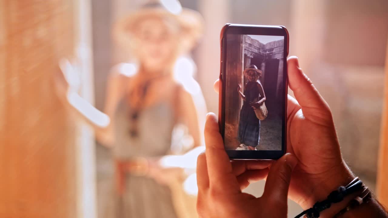 Man with smartphone taking photos of woman at ancient monument