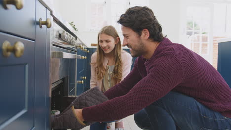 father with disappointed teenage daughter taking out burnt homemade cupcakes from the oven