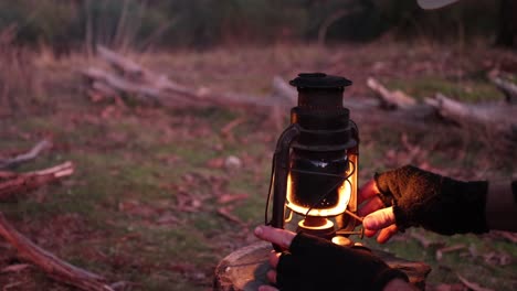 a bushman lights a traditional lantern out in the bush for light