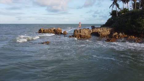 girl standing on rock on the edge of brazils ocean pan in shot to cute girl