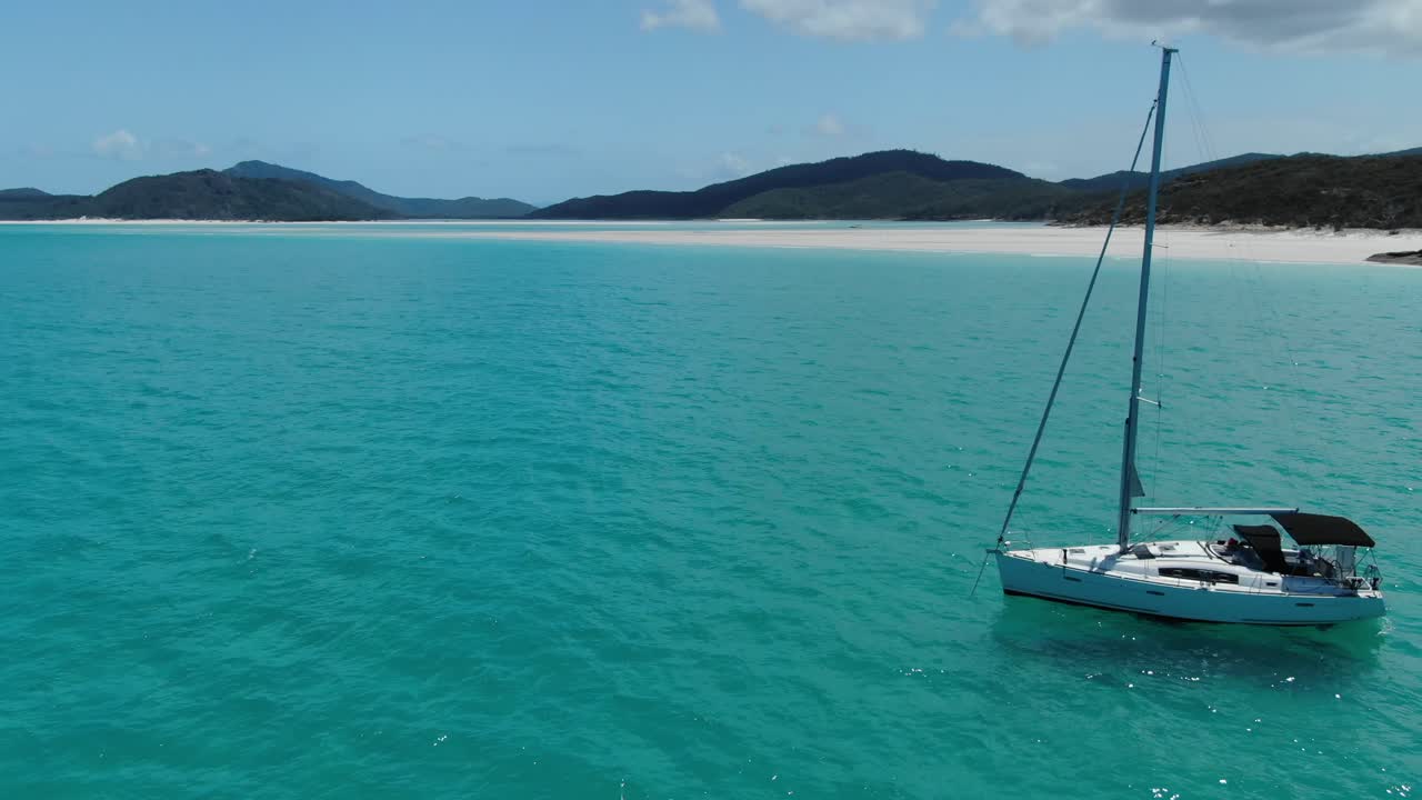 un yate de vela blanco está anclado frente a la costa de la increíble playa white haven, australia, órbita de drones y sobrevuelo