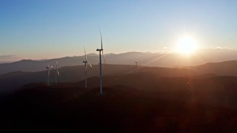 puesta de sol iluminando turbinas eólicas en colinas onduladas, capturada desde una perspectiva aérea haciendo hincapié en la energía renovable