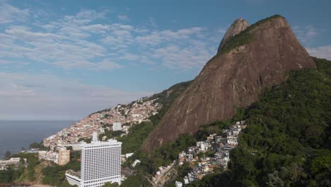 toma aérea ascendente que revela los picos de las montañas de los dos hermanos en río de janeiro con la favela de vidigal en sus empinadas laderas.