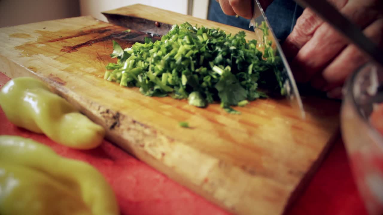 primer plano de un chef cortando cilantro en la tabla de cortar para agregarlo a la ensalada