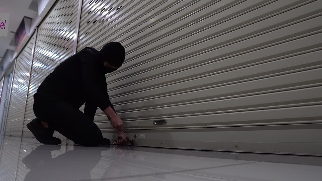 un gato ladrón irrumpiendo en una tienda fuera de horario usando una cerradura, vestido con un traje negro y un pasamontañas.