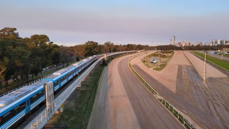 incoming mitre train running on railroad with downtown cityscape along the skyline at sunset