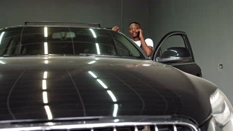 man talking on the phone while working on a car