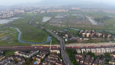 vista aérea de edificios, estación de tren, arroyos en vasai, mumbai, india - toma de avión no tripulado