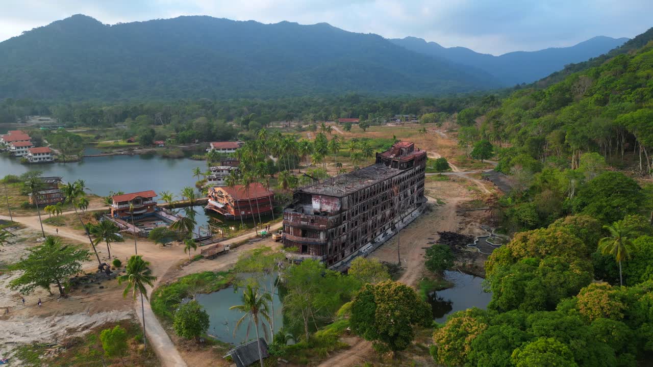 Abandoned resort showing decaying buildings, surrounded by palm trees and a lake, in Koh Chang, Thailand. Fantastic aerial view flight static tripod hovering drone