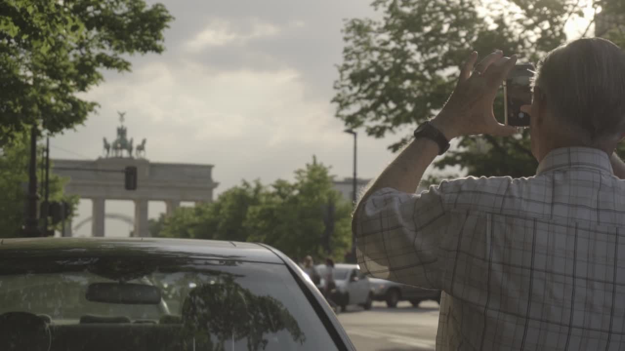 замедленная съемка: старик фотографирует смартфоном бранденбургские ворота в берлине